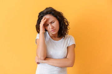 Woman suffering from head ache on color background