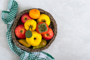 Fruit basket on a light concrete background. Seasonal fruits are a source of vitamins and health. Copy space.