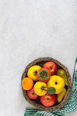 Fruit basket on a light concrete background. Seasonal fruits are a source of vitamins and health. Copy space.