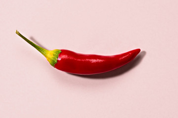 close up of a pod of red ripe little chili peppers on a pink background