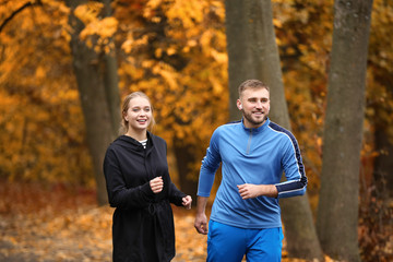 Loving young couple running in autumn park