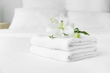 Obraz na płótnie Canvas Clean soft towels and flowers on bed