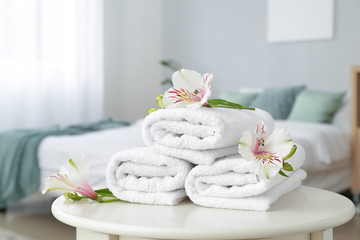 Obraz na płótnie Canvas Clean soft towels with flowers on table