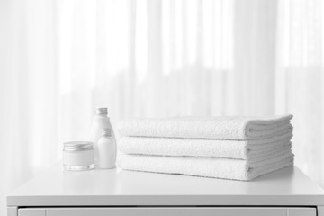 Obraz na płótnie Canvas Soft clean towels and cosmetics on table near window