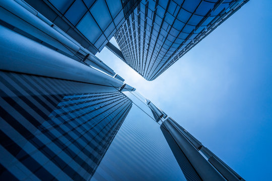 Fototapeta Bottom view of modern skyscrapers in business district against blue sky.