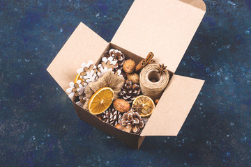 Kraft cardboard box with eco zero waste decorations for Christmas and New Year with cones, nuts, dried oranges and twine.