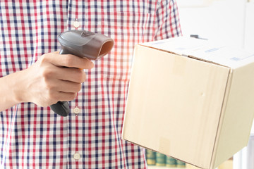 Asain business owner scanning QR code or barcode on product box with the mobile scanner. New payment and selling technology concept