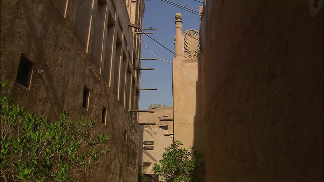 Medium low-angle still shot of two  adjacent historical buildings with wind catcher and wind tower, and decorative wall sculpture, Bastikiya, Dubai, UAE