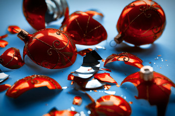 Bright orange, glass Christmas baubles broken, scattered fragments on a blue background
