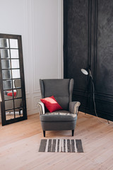 a gray armchair with a red cushion stands in a large Studio