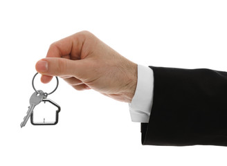 Real estate agent holding house key with trinket on white background, closeup