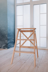 a light wooden chair stands against a light wall