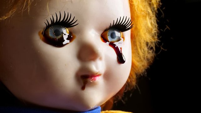Close up of old creepy doll toy with blood from eyes on it.