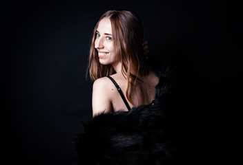 White woman in fur boa on black backdrop 