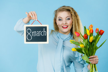 Woman holds tulips, board with text 8 march