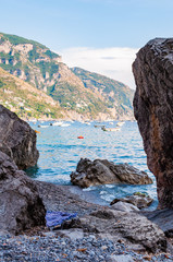 Big boulders lying on the beach, people resting, sunbathing and swimming in Tyrrhenian sea in Positano amazing medieval city on rocky mountains in Campania