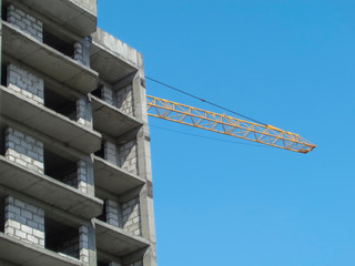 Standard-type apartment building. Central asia. Ust-Kamenogorsk (Kazakhstan). Construction crane. High-rise buildings. Construction site. Building under construction. Blue sky