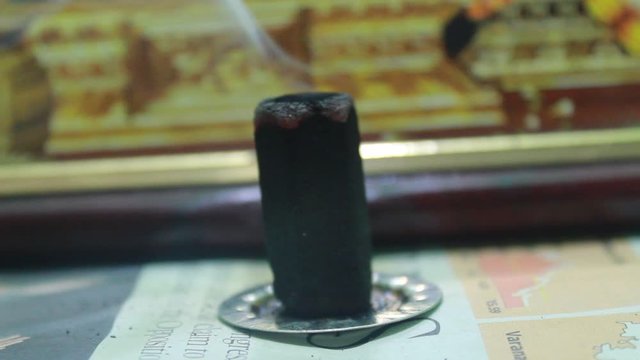 Close up shot of man lighting up dhoop batti / incense stick and it is burning with some smoke on the pooja room