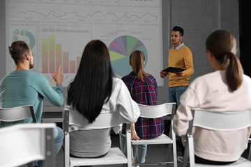 Male business trainer giving lecture in conference room with projection screen