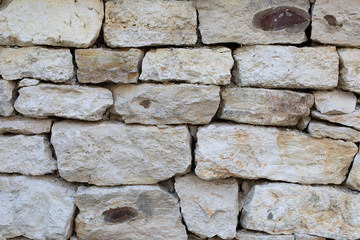 Limestone masonry, rough uneven pieces of sandstone, texture background backdrop. White gray textured surface