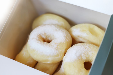 donuts with icing sugar powder in paper box