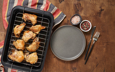 Garlic roast chicken in oven on wooden background