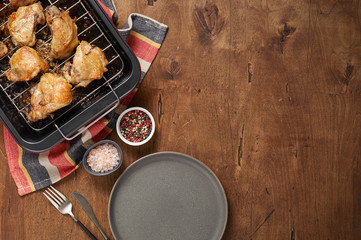 Garlic roast chicken in oven on wooden background