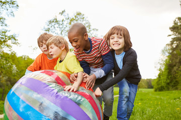 Lachende Kinder rollen einen bunten Ball