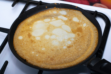 rosy pancake fried in a pan on a stove