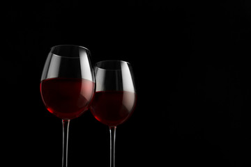 Two red wine glasses on a black background