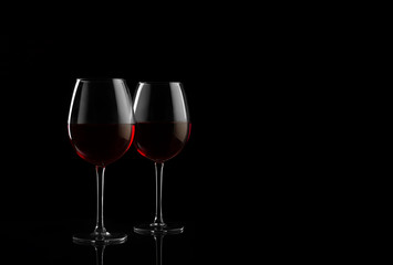 Two red wine glasses on a black background with copy space for your text