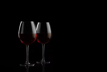 Rolgordijnen Two red wine glasses on a black background with copy space for your text © zakiroff