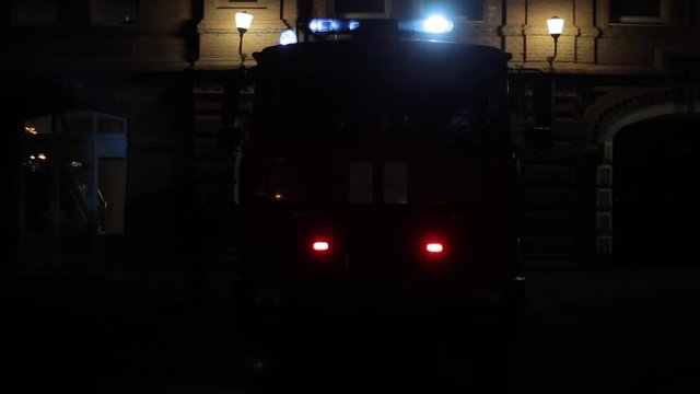 Fire engine with flashing lights in front of fire department at night. Firefighter in the front seat