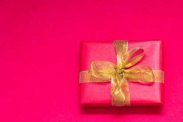 Red box with a gift, tied with a gold ribbon. Place for text, copy space.