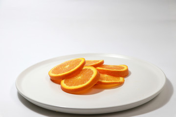The thin round pieces of orange slices put together on the white dish.