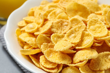 Tasty crispy corn flakes in bowl, closeup