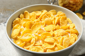 Tasty crispy corn flakes with milk in bowl, closeup