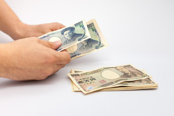hand holding and counting yen banknote, Stacked of cash 10,000 baht banknote Japan isolated on white background. Savings and investing concept Pile of cash bills amount million.