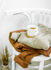  two knitted sweaters on white wooden chair
