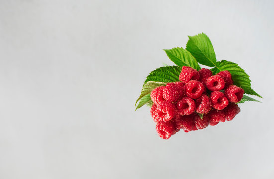 aspberries decorated with green leaves on a mirror surface