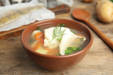 Delicious fish soup in bowl on wooden table