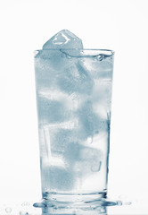one glass of water full of ice cubes, white background, blue toned object
