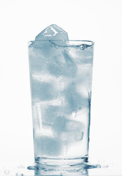one glass of water full of ice cubes, white background, blue toned object