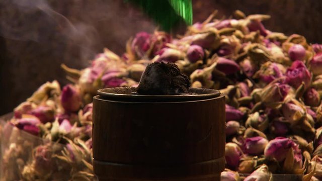 Close-up low angle still shot of burning incense in front of dried rose-flowers at a spice market. Spice Souk, Dubai, UAE