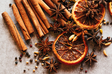 Christmas spice background. Cinnamon, dried oranges and anise on a grey background.