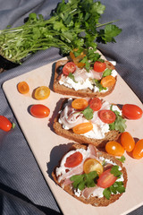 toasts with curd cheese, bacon, herbs and tomatoes