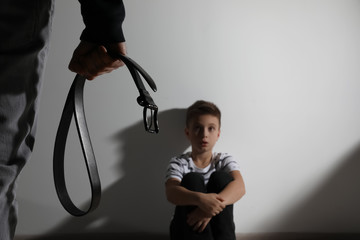 Man threatens his son at home, focus on belt. Domestic violence concept