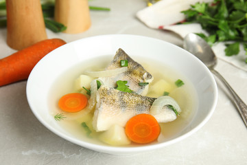 Delicious fish soup in bowl on light table, closeup