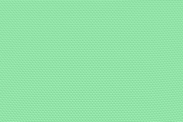 Obraz premium Light emerald green background from a textile material with pattern, closeup. Structure of the green fabric with punching texture. Perforated cloth backdrop.