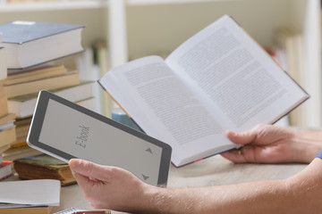 Man holding a modern ebook reader and book in library